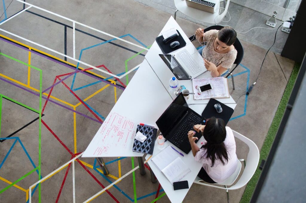 Two coworkers talking at a desk.