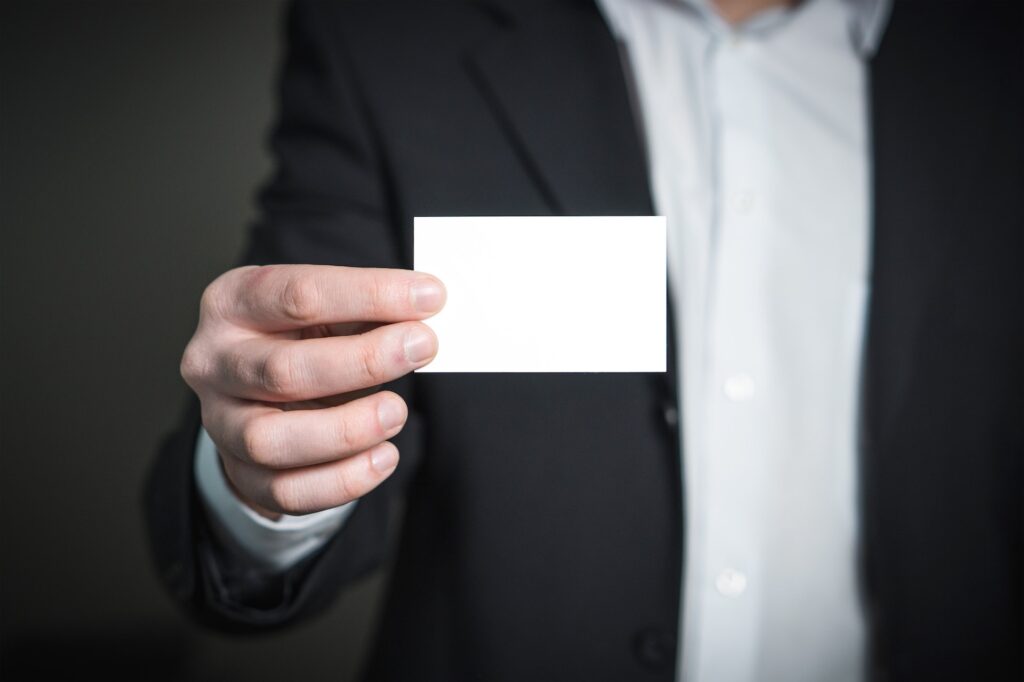 A blank micro business card held out by a person in a suite.