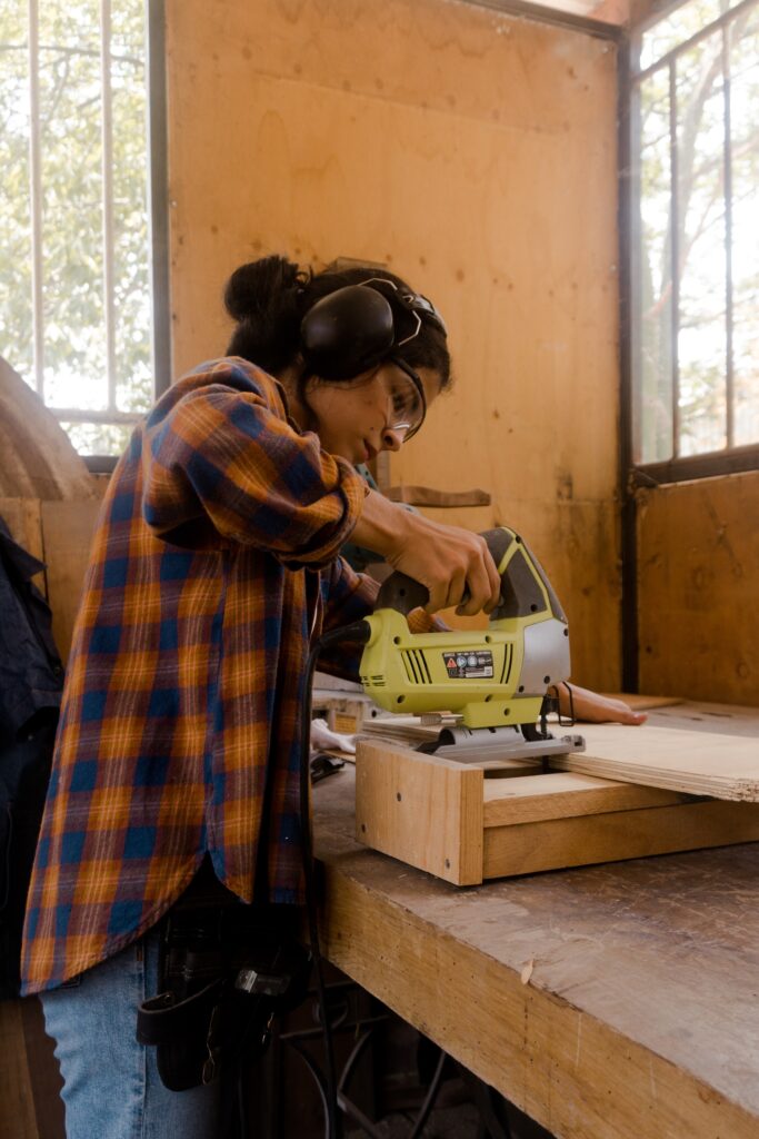 Woman carpenter sawing a piece of wood