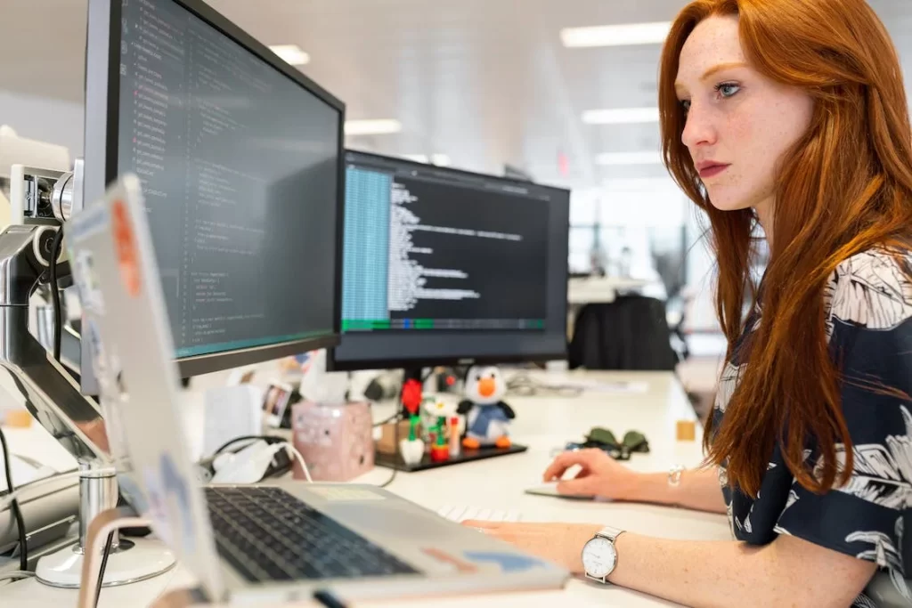 Woman working at her desk with multiple monitors.