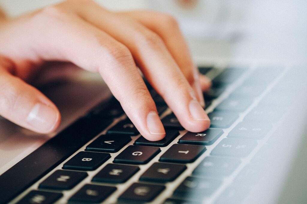 A hand typing on a laptop keyboard.
