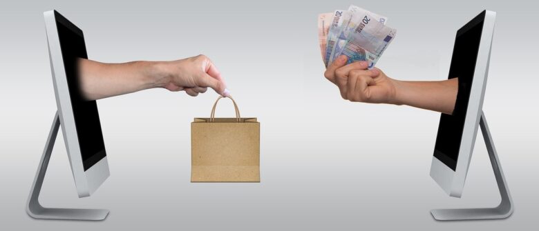 A hand with a shopping bag going through a computer screen to reach the computer screen that is accrues from it with a hand that has money.