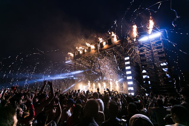 Crowd of people at a music festival with streamers and lights.