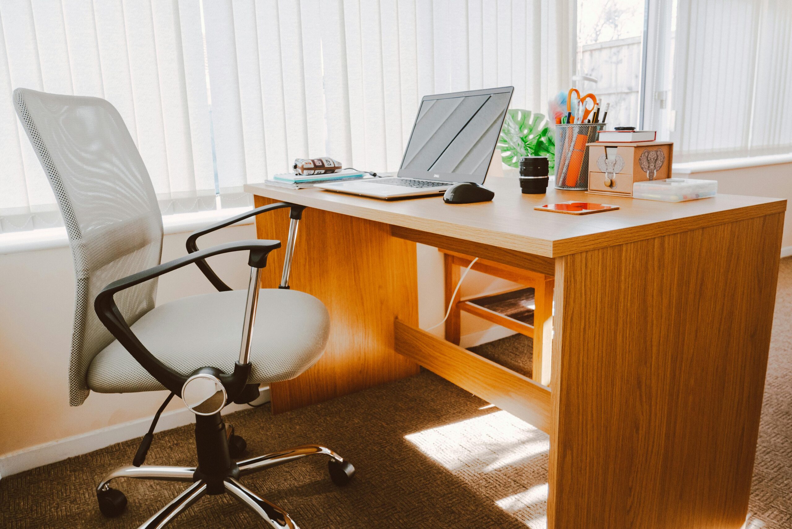 A laptop sitting on a desk and a chair